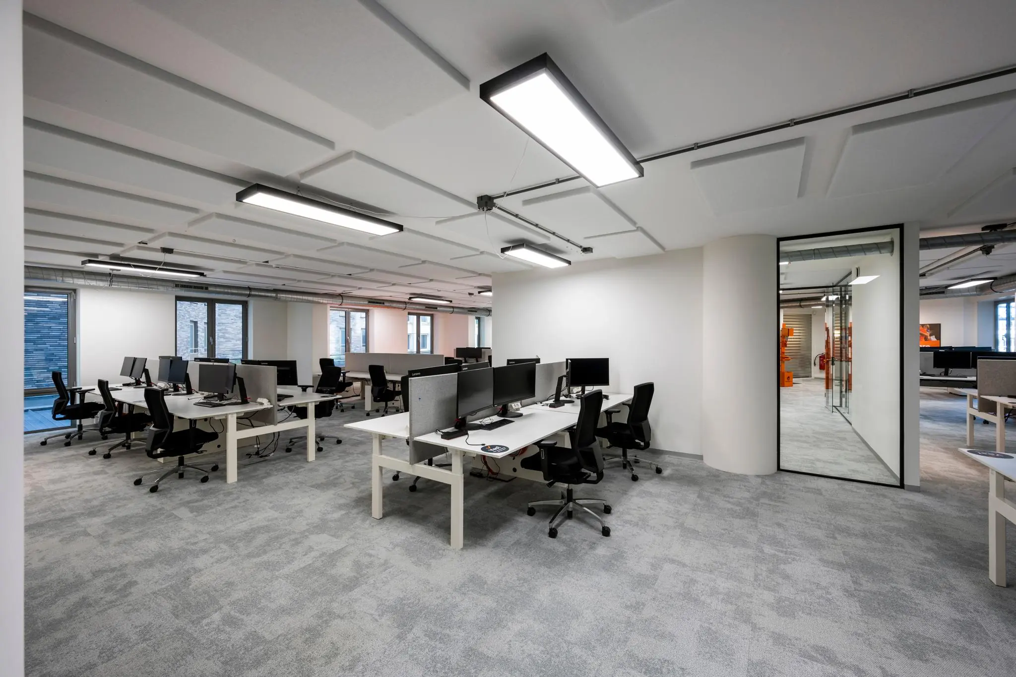 Moderne, open kantooruimte aan de Harry Banninkstraat met meerdere werkplekken, bureaustoelen en computerschermen.